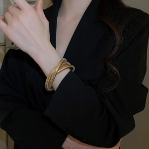 Detail of gold spiral twisted bangle worn by model with high-gloss metallic finish