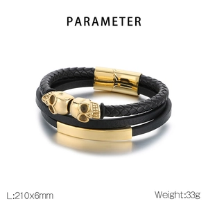 Detail of multi-layer black braided leather bracelet with golden skulls and magnetic clasp