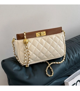 Detail of quilted leather shoulder bag with gold ball chain and metal turn-lock
