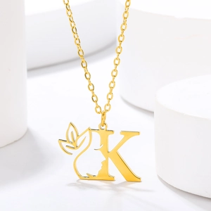 Macro shot of gold-plated letter K pendant with female profile and leaf design
