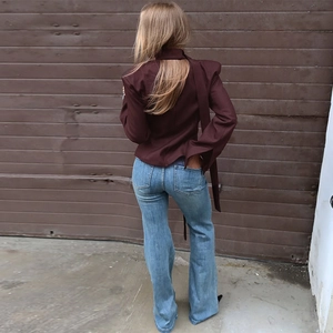 Rear view of model wearing dark red slim blazer and blue denim flared trousers