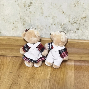 Dettaglio di portachiavi orsetto di peluche con abiti a quadri rossi e neri su pavimento