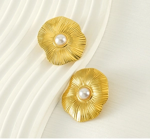 Gros plan de boucles d'oreilles pétales en or 18k avec perle centrale et texture ondulée