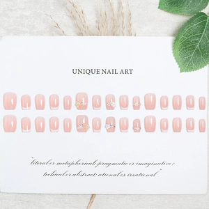 Short square press-on nails with nude pink base, classic French tips and 3D floral accents