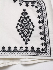 Macro shot of intricate black geometric embroidery on premium white fabric vest