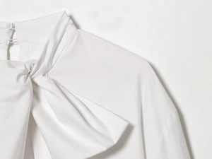 Détail d'une chemise en popeline blanche avec col à nœud et bouton à l'arrière du col