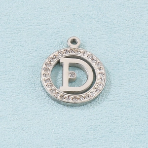 Macro shot of silver titanium steel circular pendant with letter D and sparkling crystals