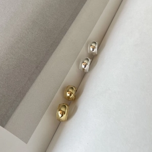 Detail of gold and silver polished half-hoop earrings with beaded edge craftsmanship