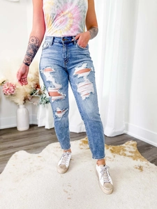Gros plan sur un jean bleu clair délavé avec détails déchirés sur parquet