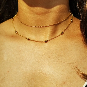 Minimalistische zweilagige Edelstahlhalskette mit goldenen ovalen Perlen an feinen Ketten