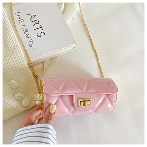 Detail of pink quilted cylindrical bag with golden clasp and pearl chain accent