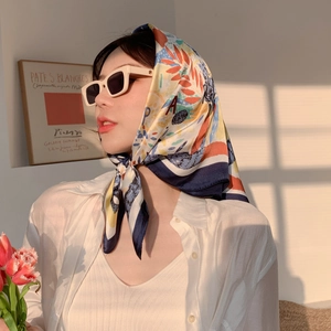 Detail of colorful paisley silk scarf styled with sunglasses under warm sunlight