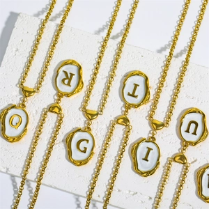 Detailed close-up of 18K gold-plated initial necklaces on white textured stones