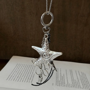Macro shot of vintage silver starfish pendant with spiral texture over an open book