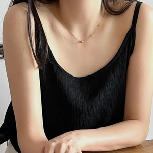 Close-up of elegant gold beaded snake chain necklace worn on collarbone with minimalist style