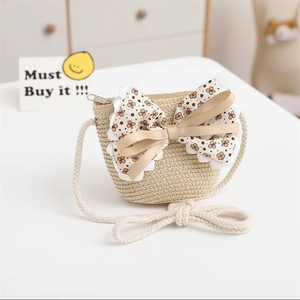 Detail of warm beige kids straw crossbody bag with floral lace bow and metal zipper
