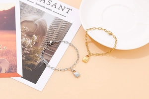 Detail shot of a minimalist gold padlock pendant on a textured rectangular link chain