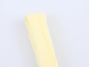 Detail of light yellow textured crepe fabric showing vertical pleated wrinkles on a dress