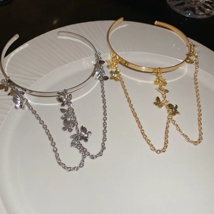 Detailed macro view of gold and silver butterfly tassel charms on elegant metal bands