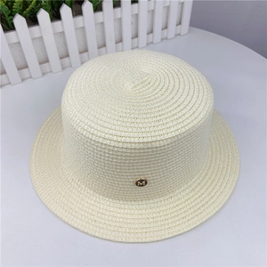 Detail view of a cream woven boater hat featuring a gold-rimmed metal M logo on the front
