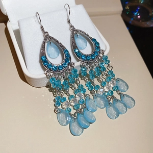 Macro shot of vintage boho tassel earrings with blue crystals on a white jewelry box