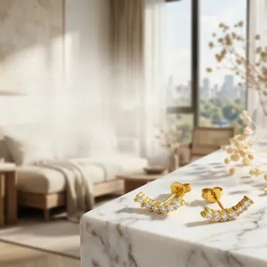 Detail of 18K gold-plated curved earrings with sparkling cubic zirconia on marble surface