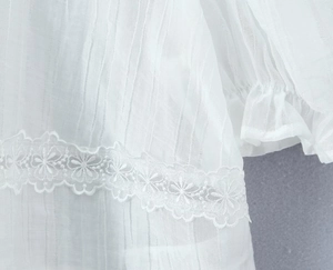 Détail d'une blouse blanche en mousseline semi-transparente avec dentelle et rayures
