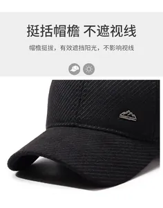 Close-up of black corduroy baseball cap with mountain metal badge and sport engraving