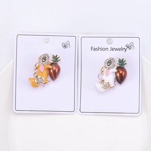 Detail of two rabbit holding carrot brooches with rhinestones on fashion jewelry cards