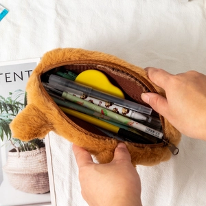 Close-up showing a hand opening the zipper of a large capacity Capybara plush pencil case