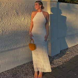 Detail of white pleated halter dress featuring delicate textured fabric in sunset light