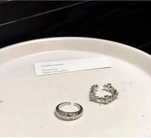 Dettaglio di anelli d'argento con motivo a stelle e croce gotica su un piatto bianco
