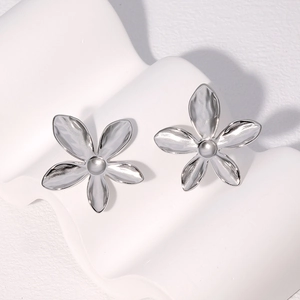 Boucles d'oreilles fleurs argentées à cinq pétales sur support artistique blanc