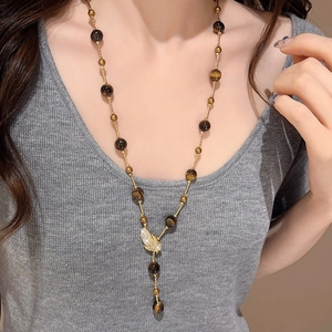 Tiger eye beaded necklace with a golden sparkling leaf pendant on a female model