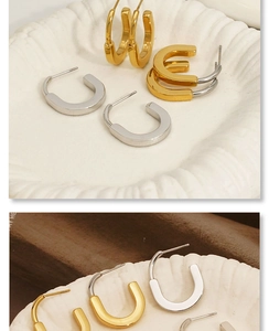 Detail showing gold and silver U-shaped stainless steel earrings on a textured tray