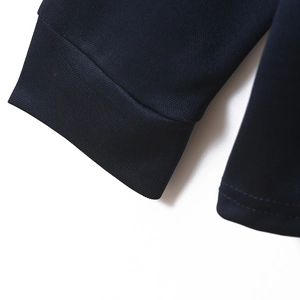 Detail shot of navy polo shirt featuring ribbed cuffs and high-quality double-stitched hem