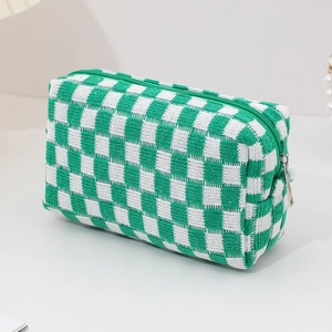 Detail of green and white checkered knit makeup bag with smooth zipper closure texture