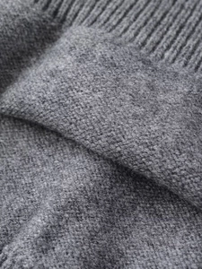 Gros plan d'un pull gris en tricot montrant la texture douce et les motifs de maille