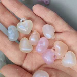 Close-up of iridescent heart-shaped acrylic beads with a pearlescent finish for DIY jewelry