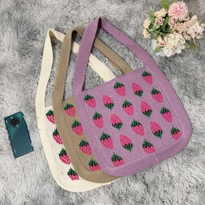 Detailed top view of knitted strawberry tote bags in purple, khaki, and cream white colors