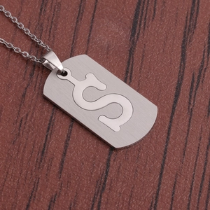Vue macro d'un collier en acier inoxydable avec pendentif S sur surface bois sombre