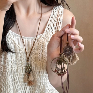 Bohemian woven leather necklace with heart charm and tassel worn by a model