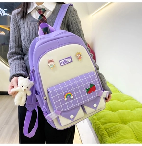 Detail of purple plaid school backpack with cute strawberry patch and bear keychain charm