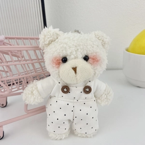 Dettaglio del simpatico orsetto di peluche in salopette a pois con pelliccia bianca