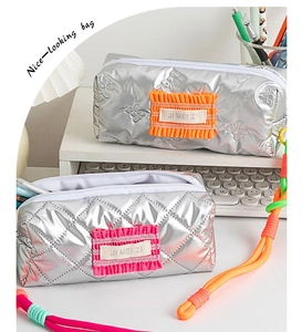Detail of silver quilted pencil cases with metallic finish and colorful accents