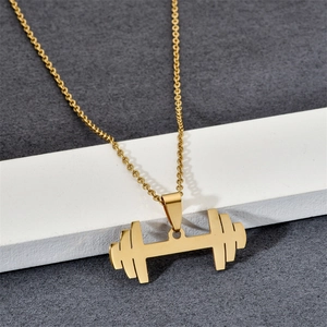 Detail shot of a golden dumbbell pendant on a stainless steel chain over a grey surface