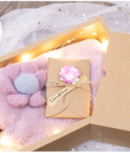 Vista macro della confezione regalo in carta kraft con peluche rosa, fiore e biglietto
