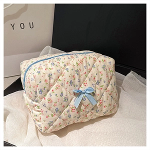 Close-up of floral quilted cotton makeup bag with blue ribbon bow and zipper detail
