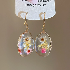 Detalle de pendientes hechos a mano con hilo de oro y flores secas naturales reales