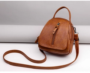 Detail of vintage brown pebble faux leather crossbody bag with tassel and zipper